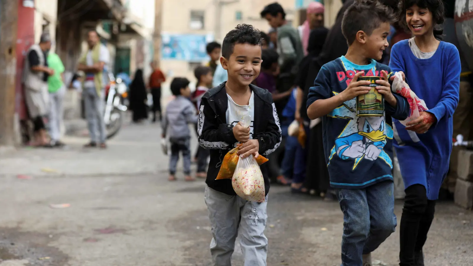أطفال يمنيون يحملون مساعدات إغاثية