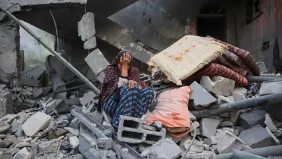 امرأة فلسطينية تجلس على ركام منزلها المدمر في غزة 