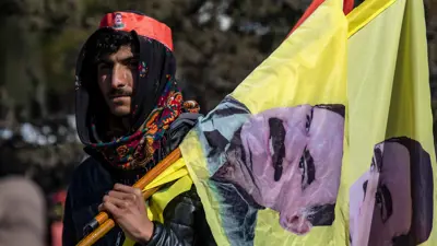 متظاهر يحمل أعلامًا بصورة عبد الله أوجلان