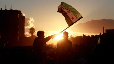 سوري يرفع العلم الجديد في دمشق
