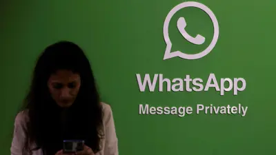 امرأة تستخدم هاتفها عند شعار واتساب