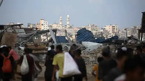 غزيون عائدون بأكياس من نقطة توزيع أغذية 