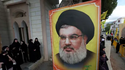 أشخاص يقفون بالقرب من صورة لحسن نصر الله