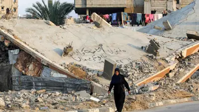 سيدة تسير وسط مبان مدمرة في غزة