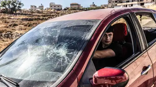 شاب فلسطيني يقود مركبة تضررت على يد المستوطنين 
