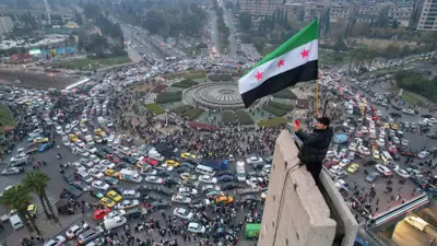 سوري يلوح بعلم الاستقلال في دمشق