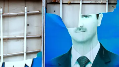صورة متضررة للرئيس السوري بشار الأسد في مدينة القامشلي