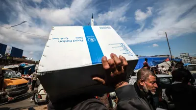 فلسطينيون يحملون صندوقًا من حصص طعام قدمها برنامج الغذاء العالمي في رفح، جنوب قطاع غزة