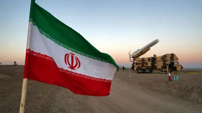 علم إيراني يظهر بالقرب من صاروخ خلال مناورة عسكرية بمشاركة وحدات الدفاع الجوي الإيرانية، إيران
