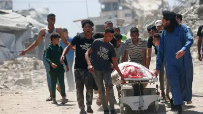 مواطنون يسحبون أحد الأسرة العلاجية من مستشفى في غزة