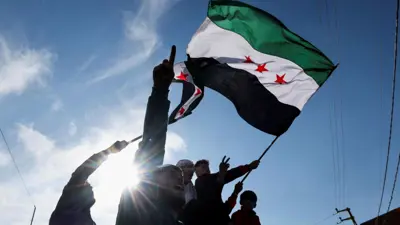 أشخاص يرفعون علم سوريا الجديد