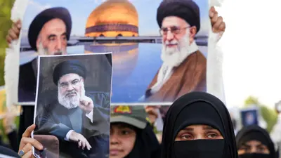 امرأة تحمل صورة حسن نصر الله خلال جنازة رمزية في البصرة، العراق