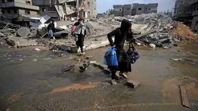 فلسطينيون يعبرون طريقًا غمرته المياه في غزة