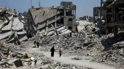 سيدتان في غزة تسيران وسط أنقاض المباني المدمرة