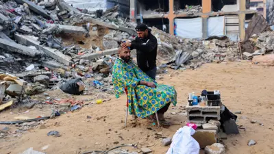 حلاق فلسطيني يعتني بزبون في كشك مؤقت في بيت لاهيا شمال قطاع غزة