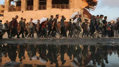 فلسطينيون يسيرون حاملين إمدادات الإغاثة