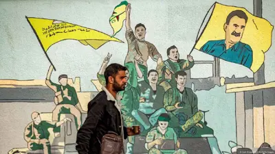 رجل يمر أمام جدارية لقسد