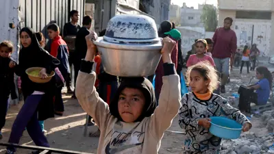 أطفال فلسطينيون يتلقون طعامًا مطبوخًا في مطبخ خيري