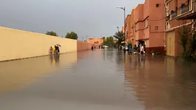 سكان يسيرون في شارع غمرته المياه في مدينة ورزازات المغربية