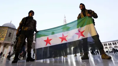 مسلحان يرفعان علم سوريا الجديد