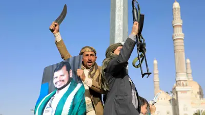 حوثيان يرفعان السلاح وصورة زعيم الميليشيا عبد الملك الحوثي